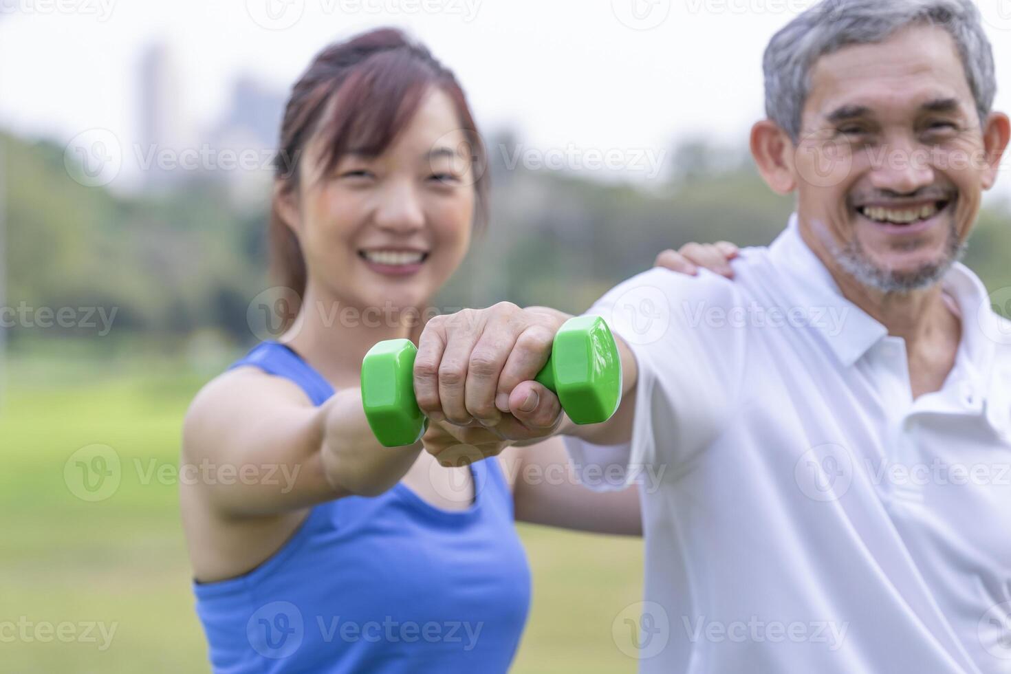 senior man doing exercise with dumbbell with trainer elderly having physical activity in the park photo