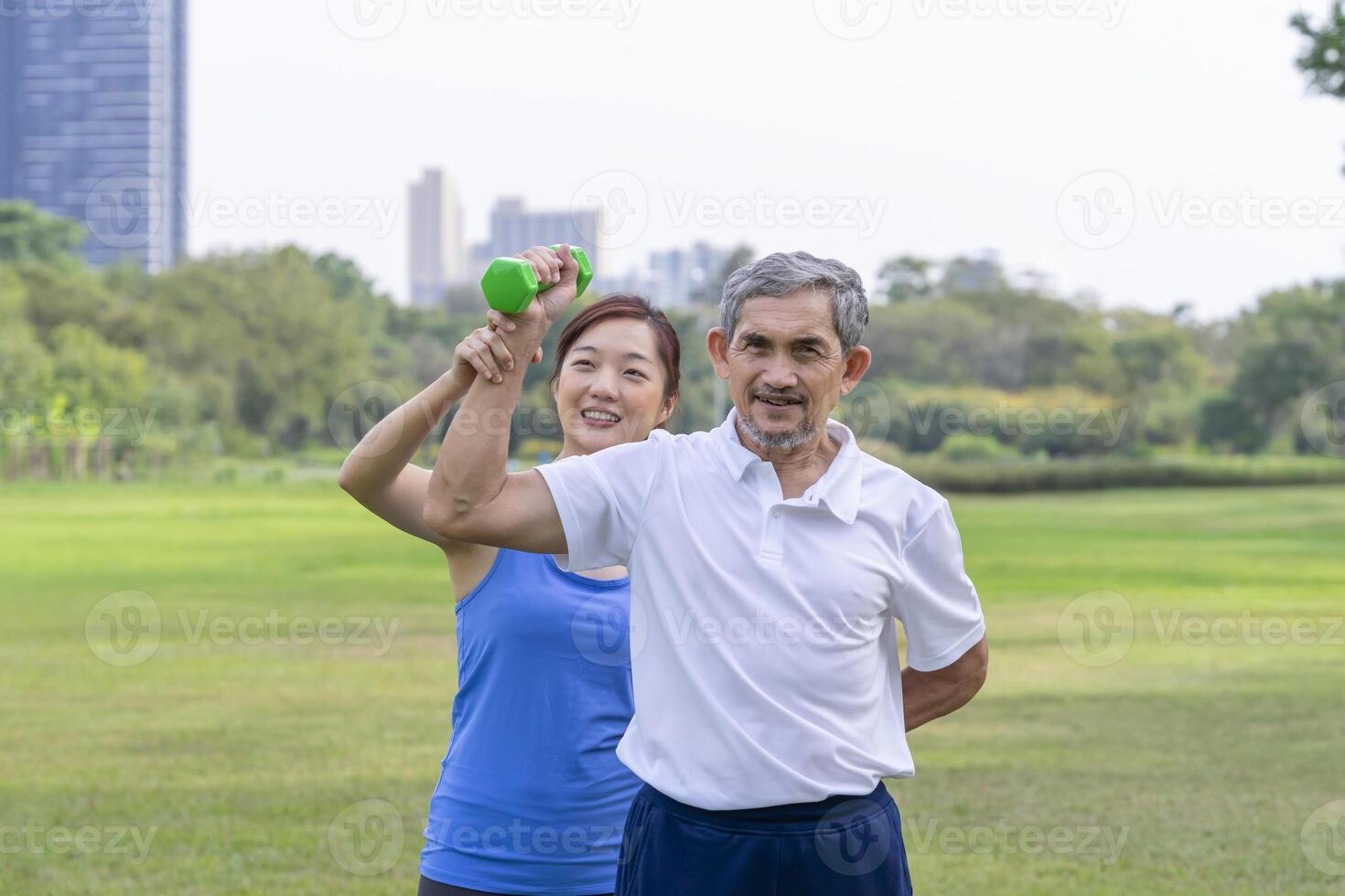senior man doing exercise with dumbbell with trainer,elderly having physical activity in the park photo