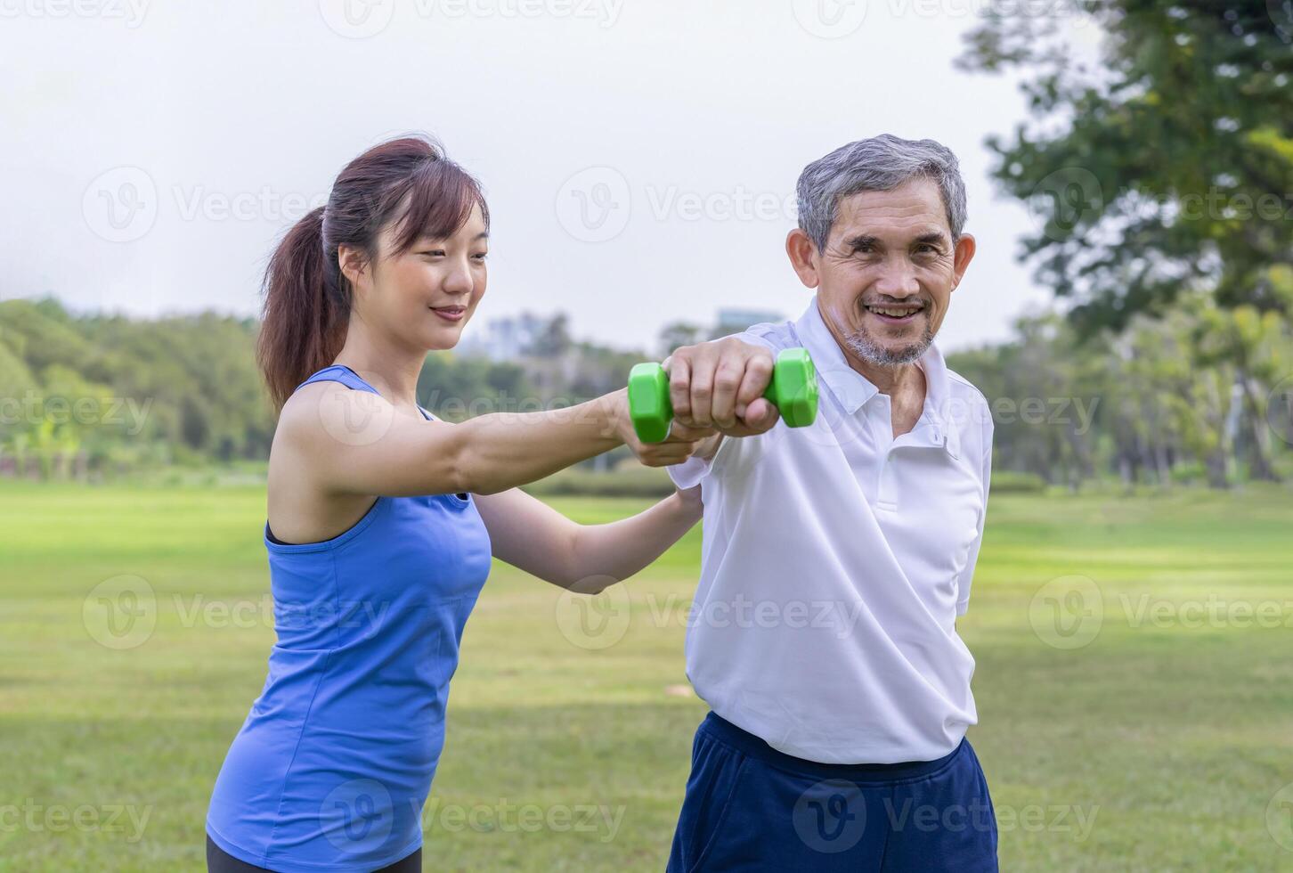 senior man doing exercise with dumbbell with trainer or physiotherapist,elderly having physical activity in the park photo