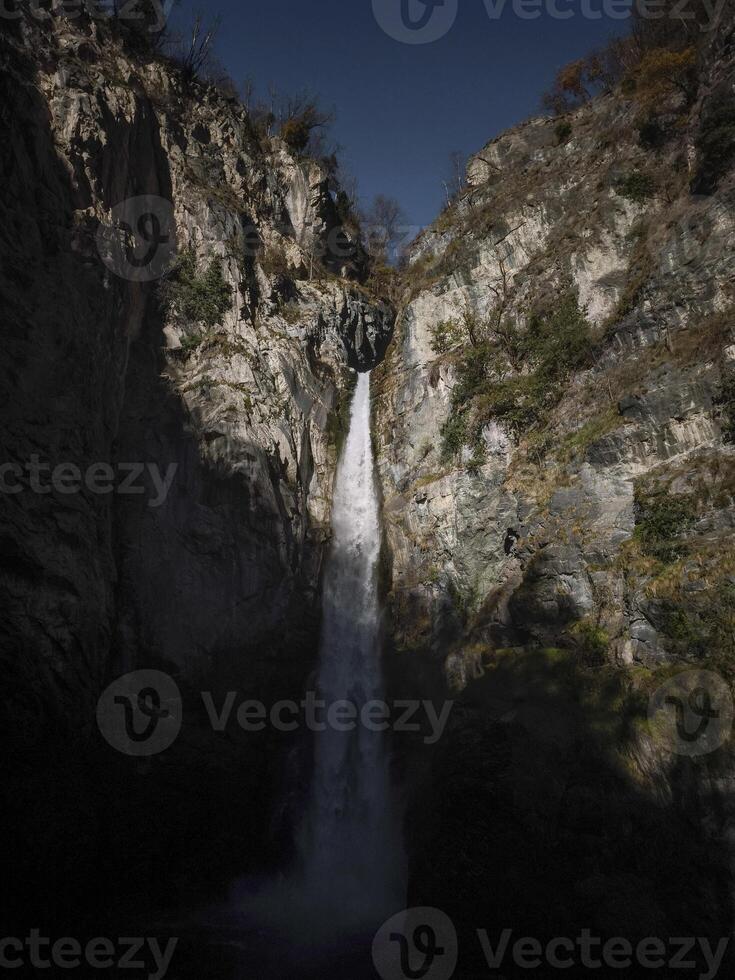 Powerful waterfall cascading down rugged cliffs in aosta, italy, surrounded by natural rock formations and bathed in soft november light Isollaz waterfall photo