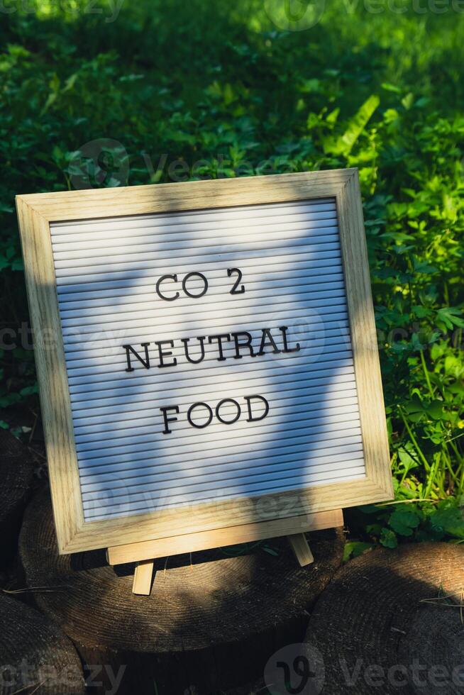 Letter board with text CO2 NEUTRAL FOOD on background of garden bed with green herb parsley. Organic farming, produce local vegetables concept. Supporting local farmers. Seasonal market photo