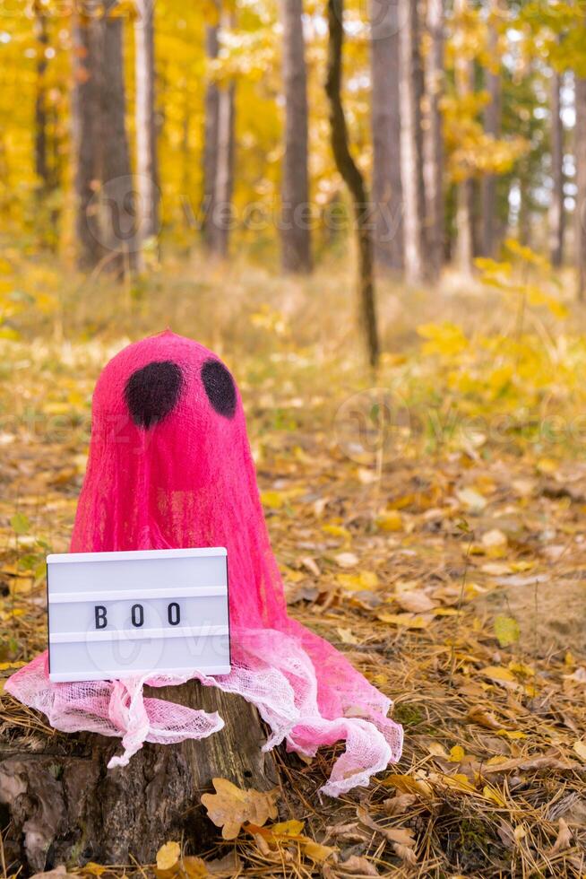 Lightbox BOO text Halloween holiday concept. Handmade pink ghost made from bandages and glue in autumn forest background. Children's art project. DIY concept. photo