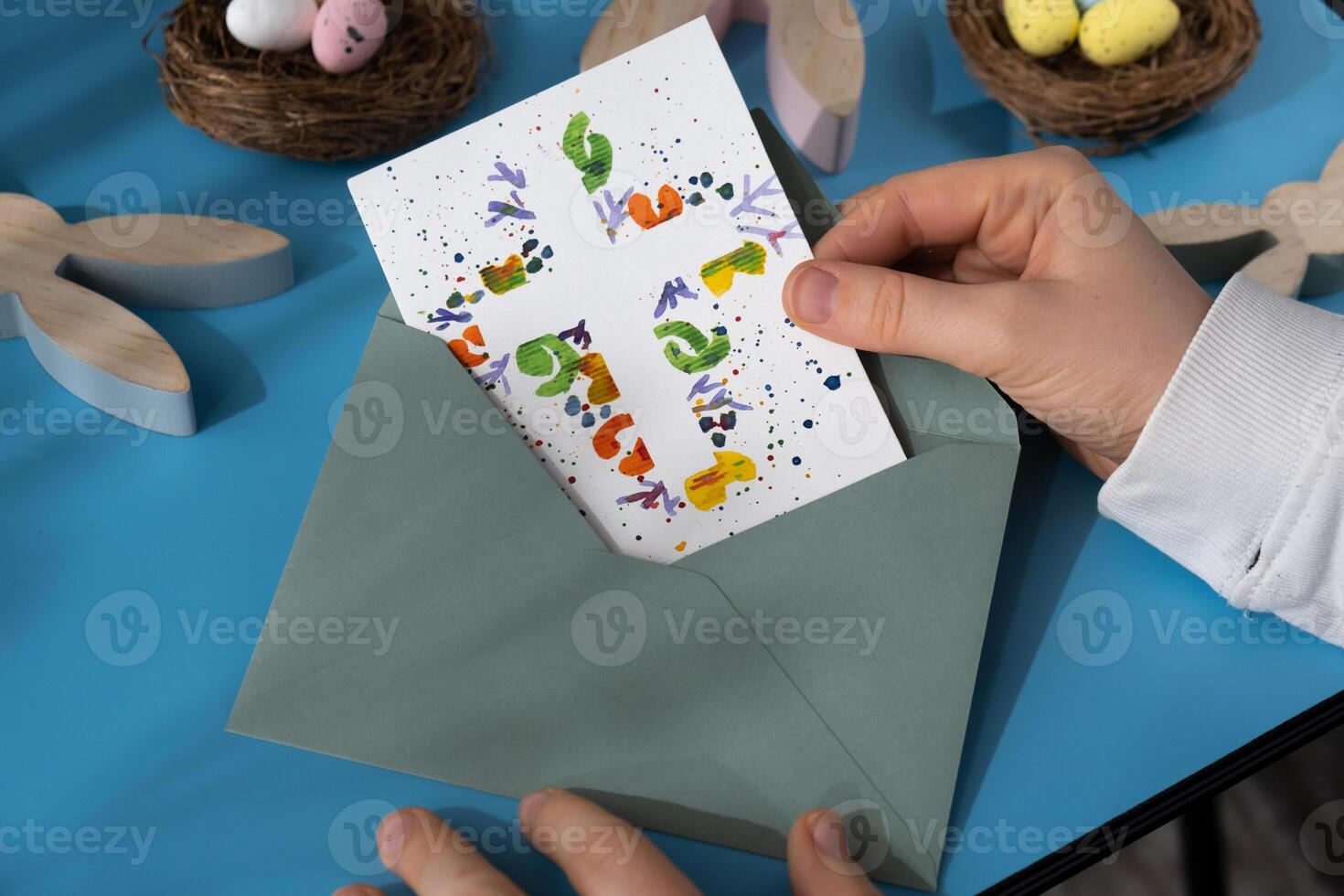 Person holding handmade greeting card with message CHRIST THE LORD IS RISEN TODAY written in beautiful handwriting. Gesture shows excitement and joy for the upcoming event. Springtime holiday gift present zero cost ideas. Creative art preparation photo