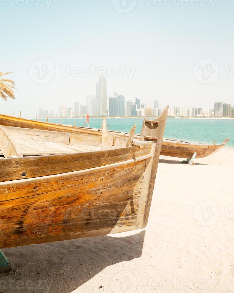 Abu Dhabi skyline with old traditional fishing boats in Heritage Village in Abu Dhabi in United Arab Emirates UAE. Couple tourist enjoy beach and visit sightseeing travel destination in UAE. photo