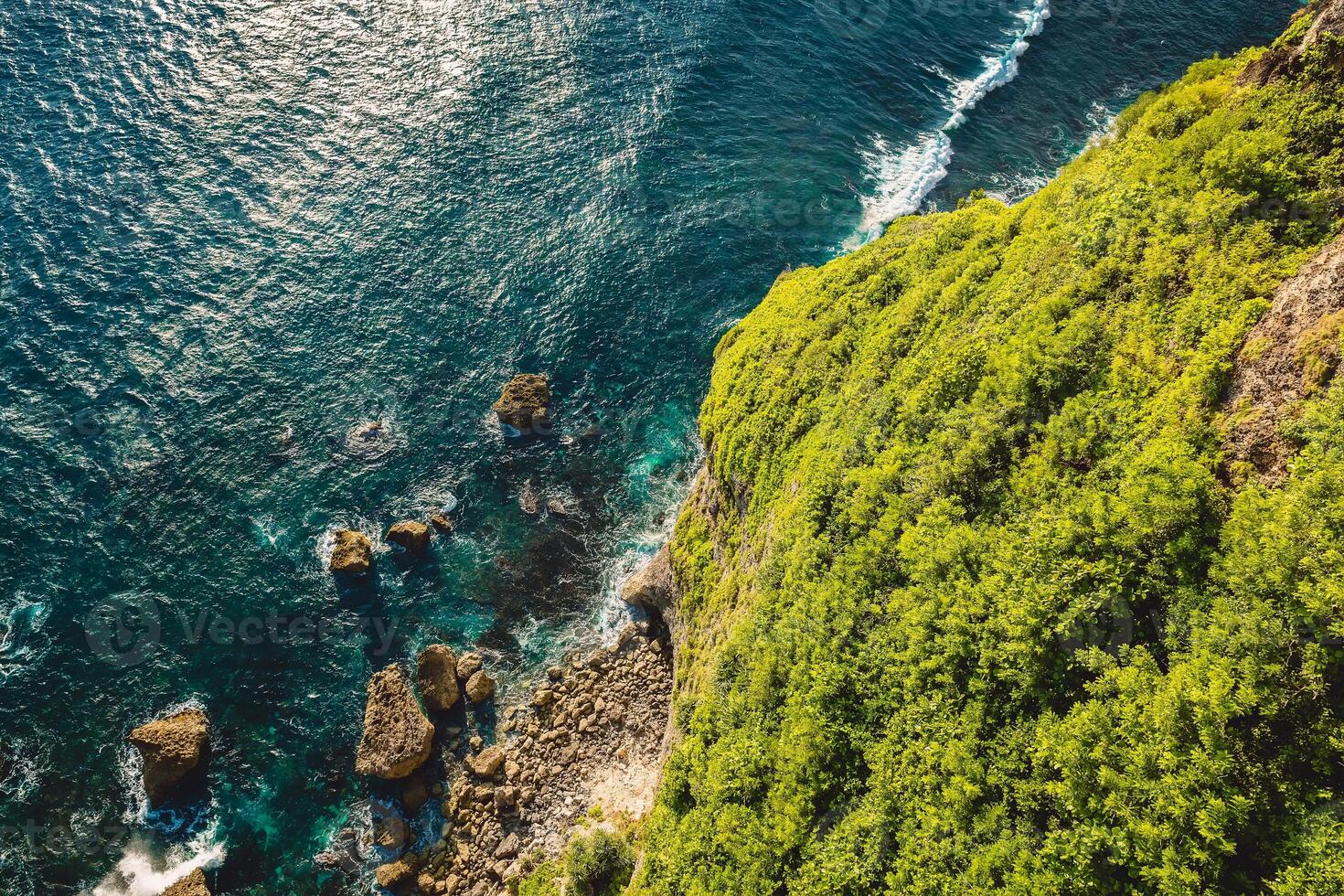 Ocean with waves crashing on stones, view from cliff coastline photo