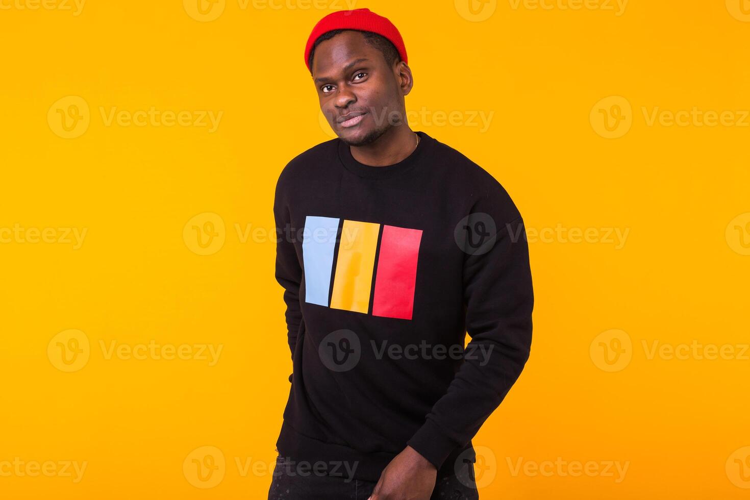 Portrait handsome young black man dressed in jeans and sweatshirt on yellow background with copy space. Street fashion and modern youth culture. photo