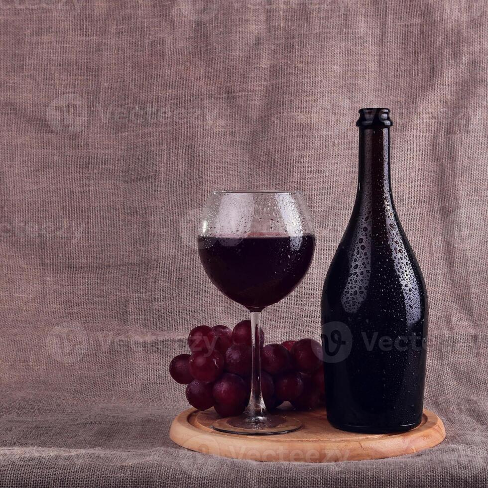 A bottle and glass of wine on a wooden board photo