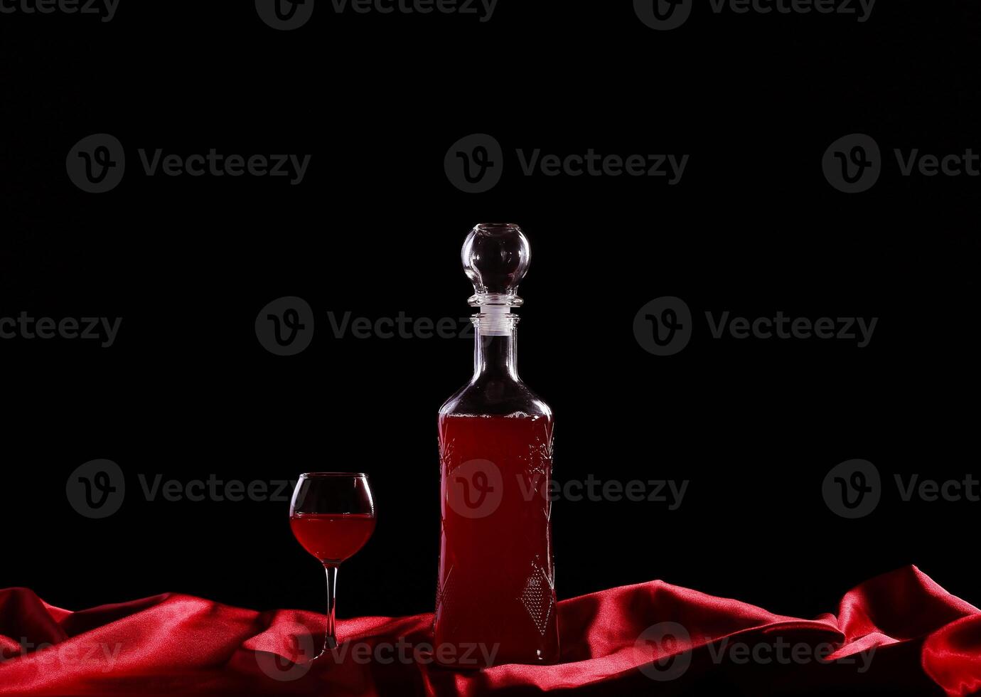 A bottle of red wine and a glass on a table photo