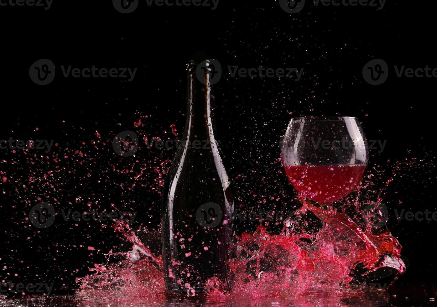 A bottle of red wine and a glass of red wine splash on a black background photo