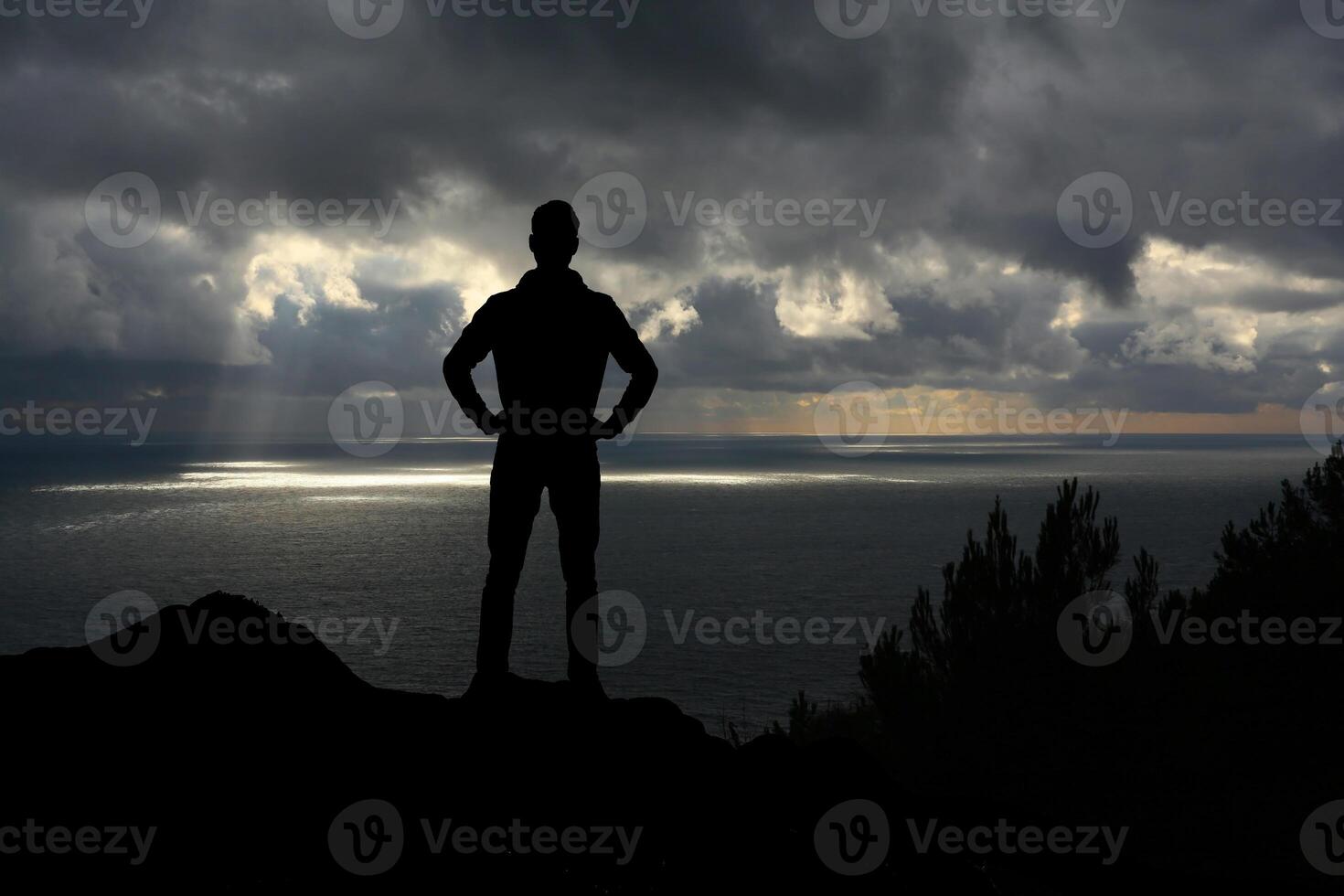 A man standing on a mountain top with his arms crossed photo