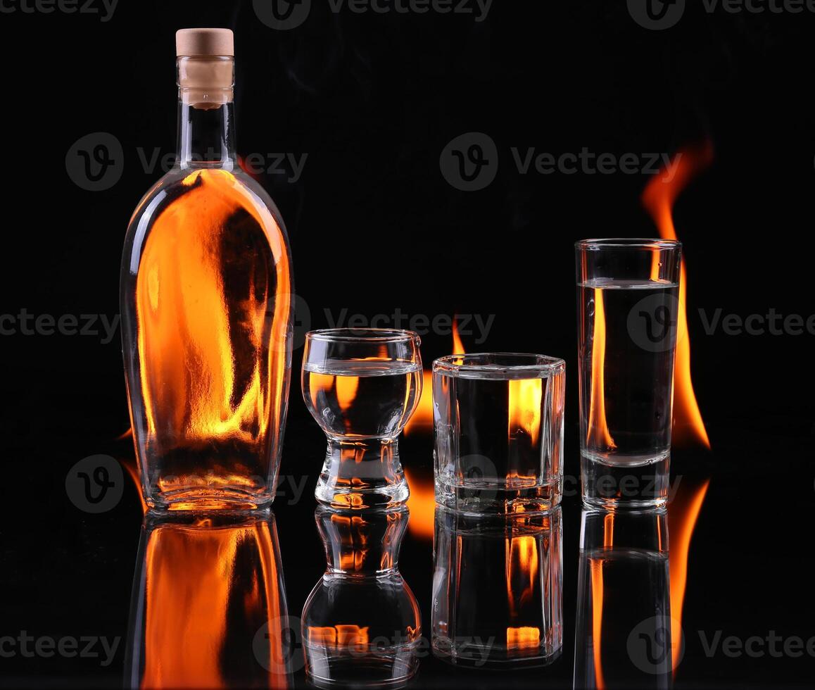 A bottle of alcohol and two glasses with flames photo