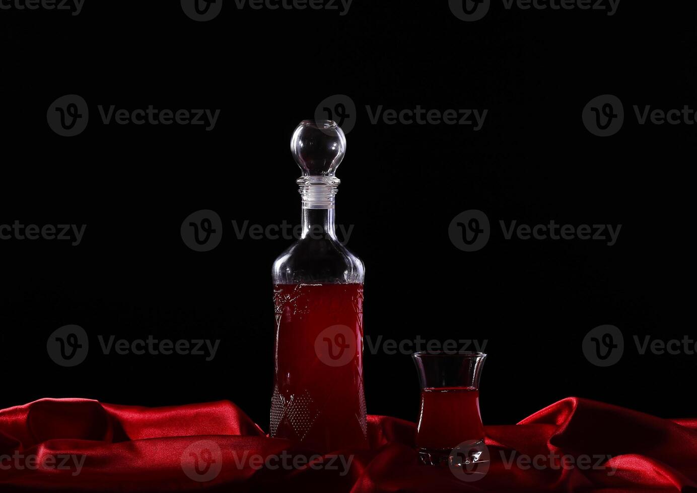 A bottle of red wine and a glass on a red cloth photo