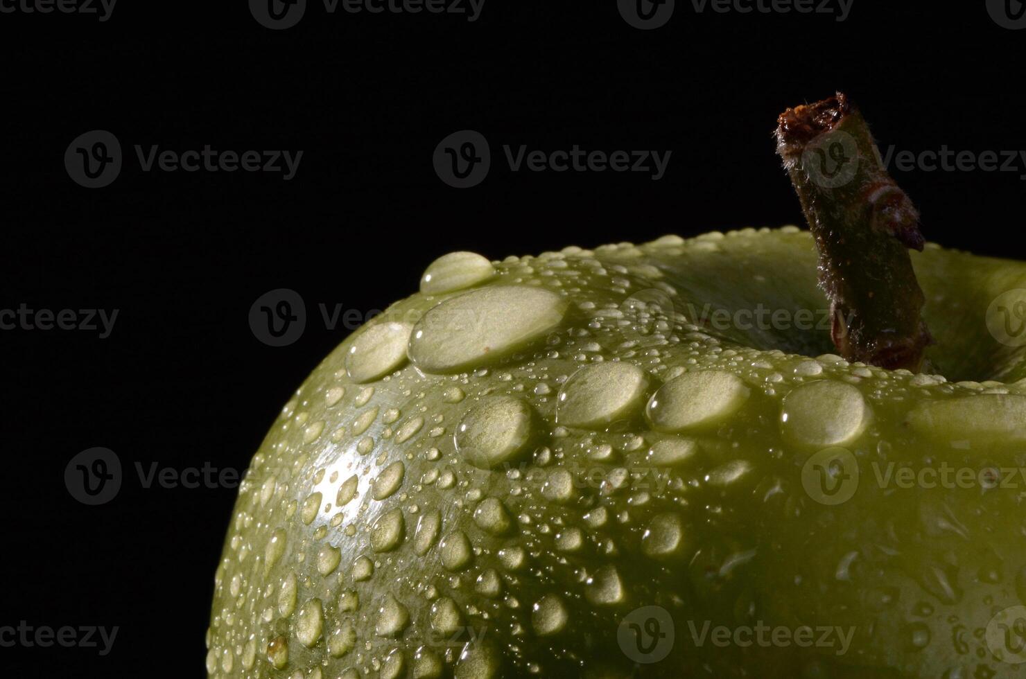 A green apple with water droplets on it photo