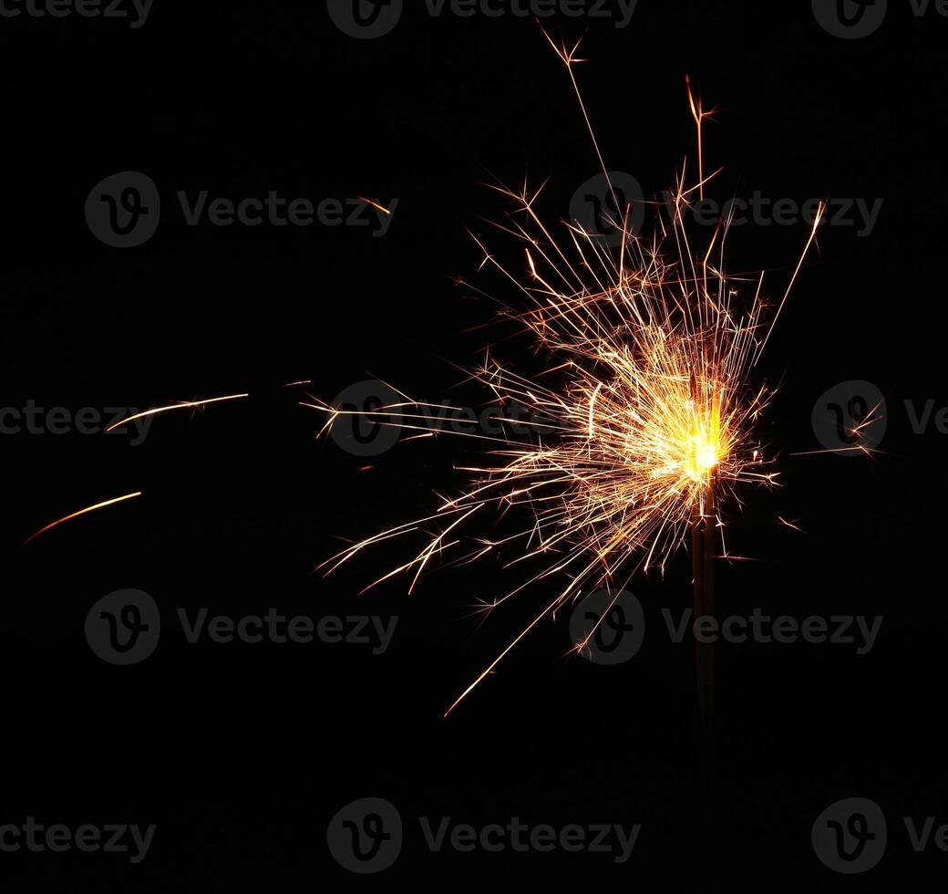 A sparkler is lit on a black background photo