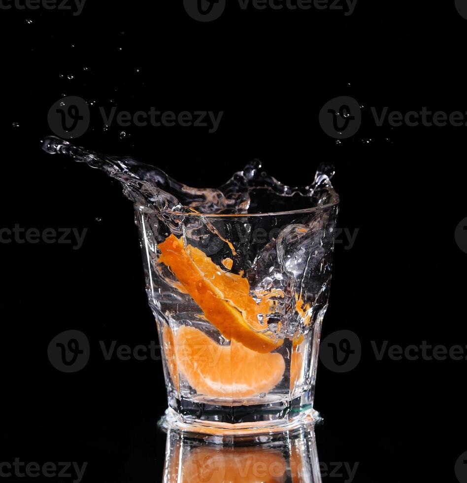 An orange slice is splashing into a glass of water photo