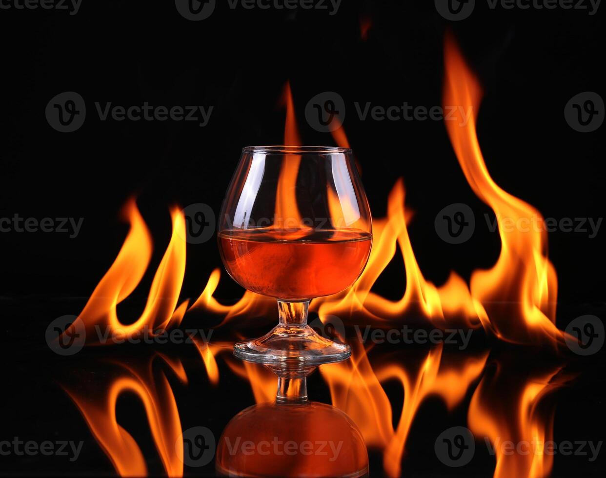 A glass of whiskey on a black background with flames photo