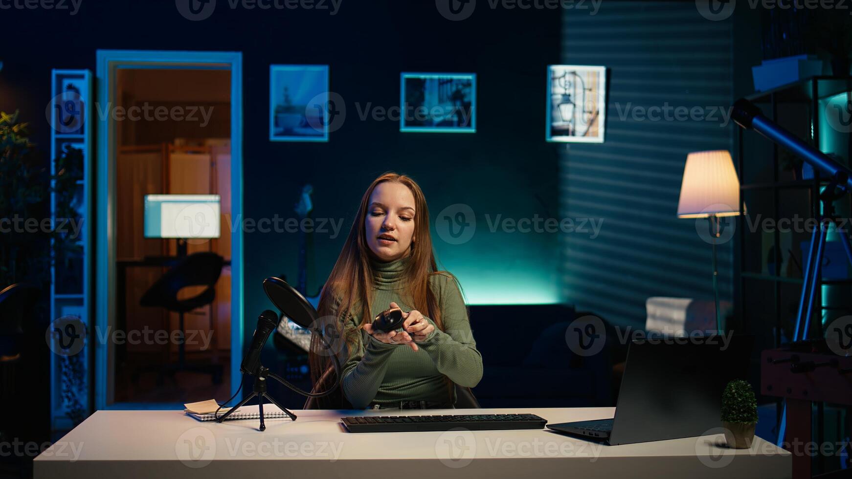 Entertainer presents keyboard and mouse from brand sponsoring , urging viewers to buy. Young girl does influencer marketing by advertising computer peripherals to audience in studio, camera B photo