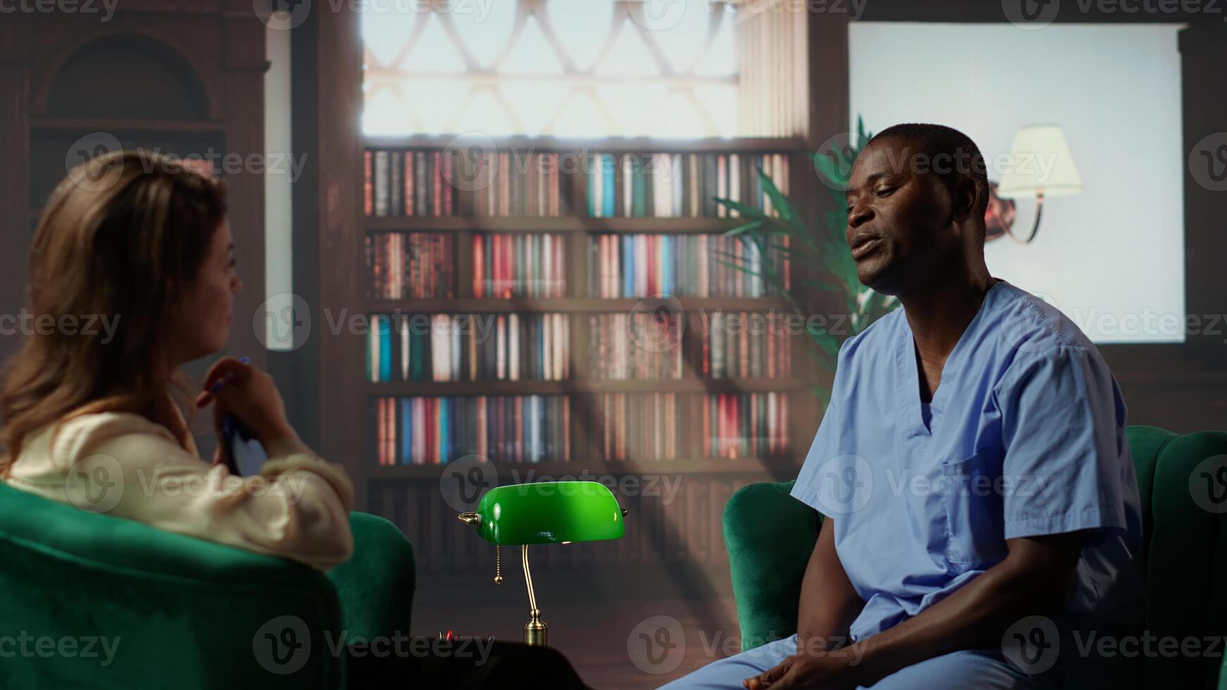 Black nurse in therapy addressing anxiety and post traumatic stress from career in hospital, assistant seeks help for PTSD and depression after losing patients, burnout. Camera B. photo