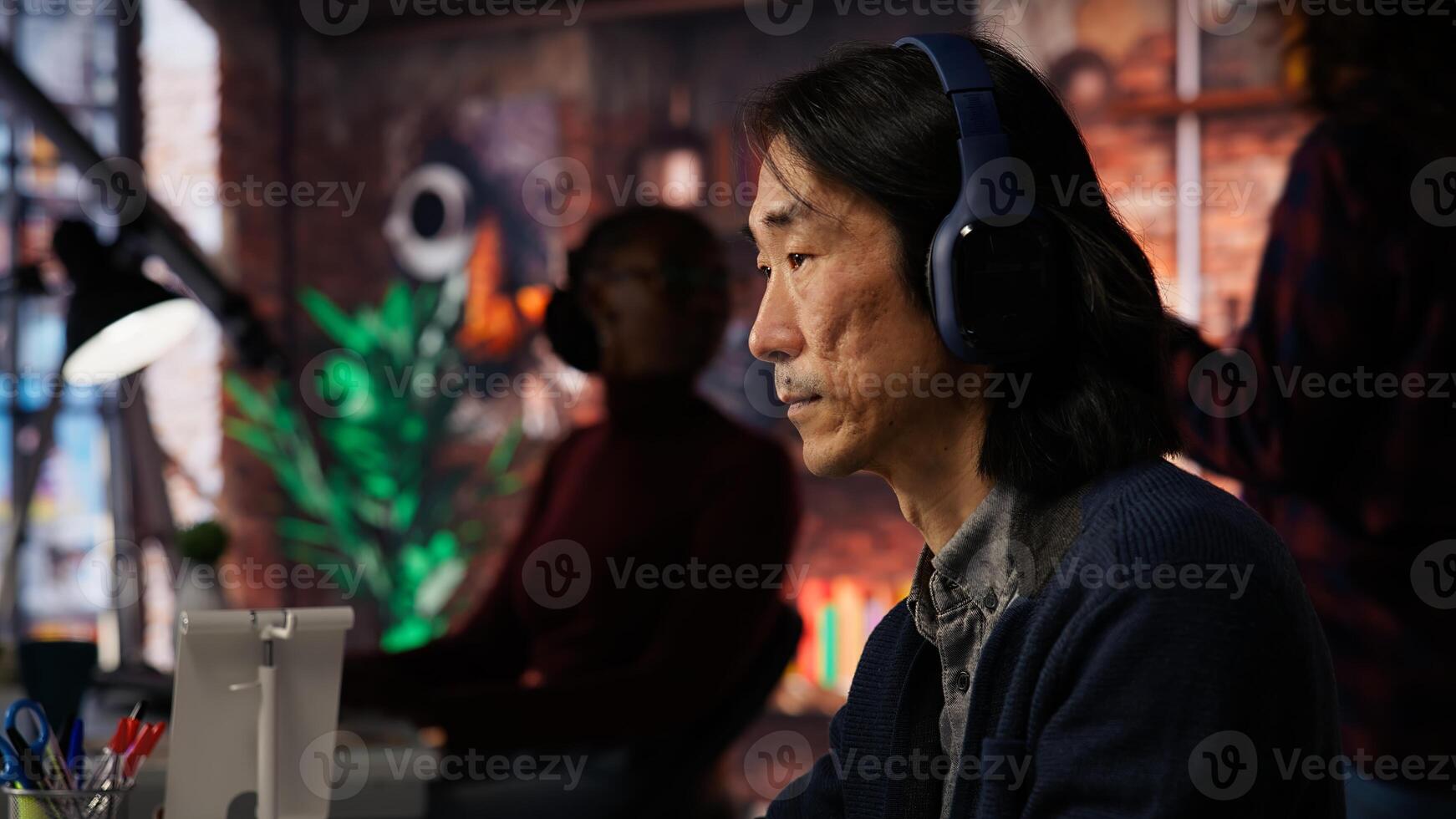 AI startup office chief technology officer listening music while coding application. Senior programmer wearing headphones, working in artificial intelligence software development agency, camera B photo