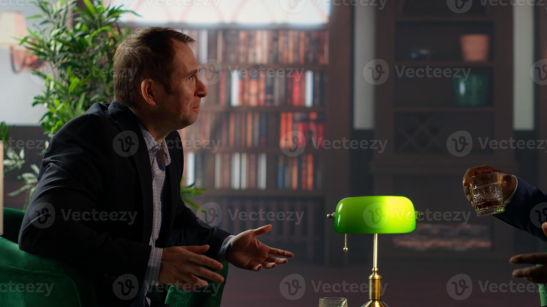 Multiethnic businessmen sharing whiskey glass in elegant library, discussing business strategy and building trust. Confident gentlemen embodying luxury and elite social culture. Camera B. photo