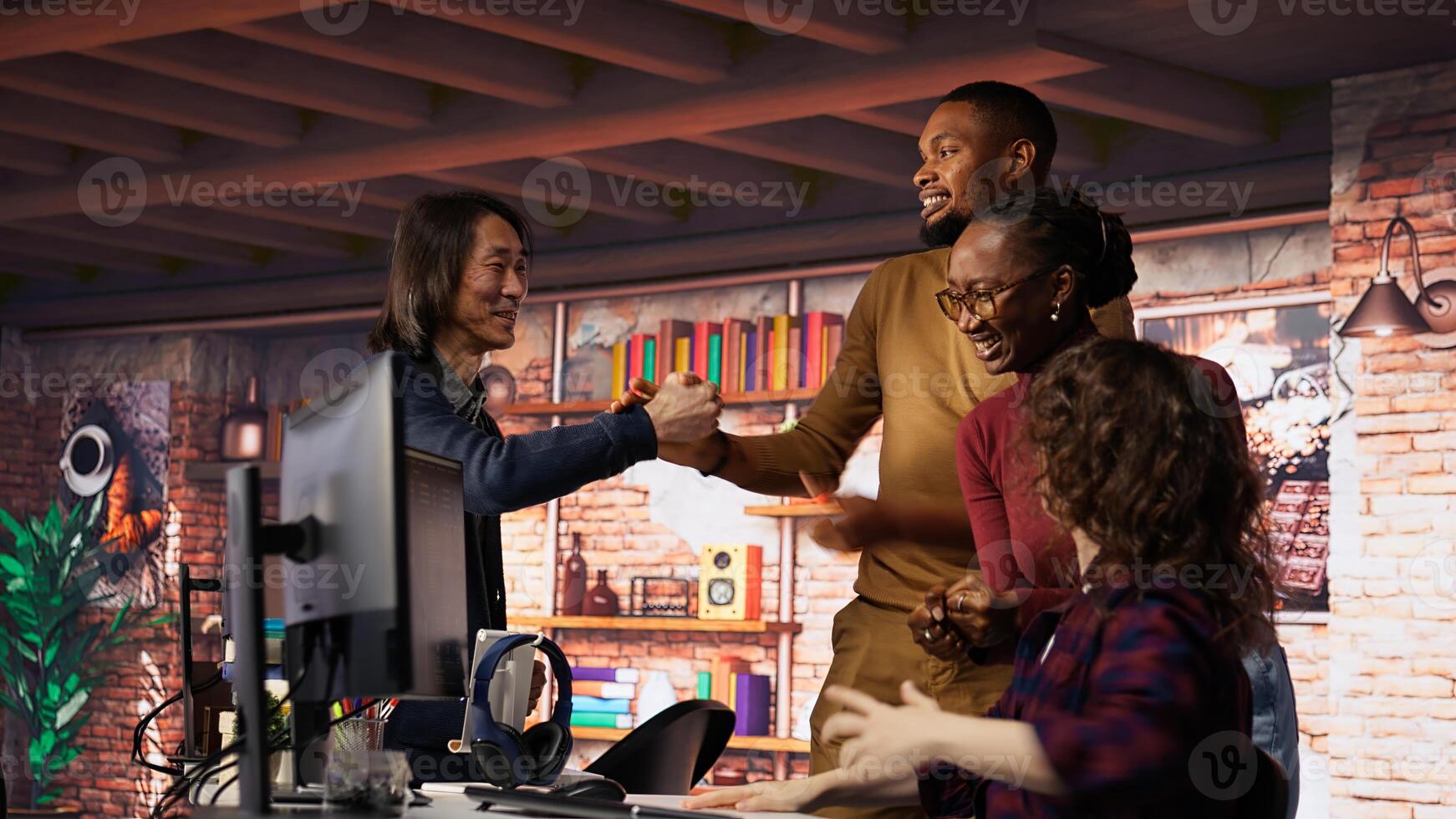 Startup team cheering after seeing live market updates showing stocks raising, doing high five. Joyous venture staff members overjoyed after becoming publicly traded company, camera B photo