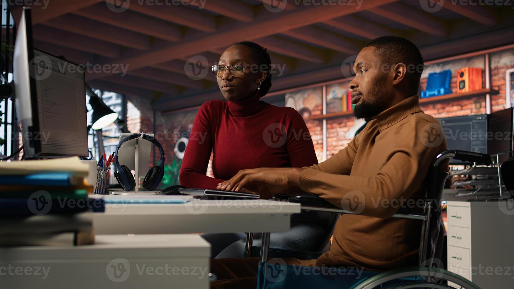 Manager offering help to startup office employee in wheelchair desk. Thoughtful supervisor checking up on software development agency worker with disability, camera A photo