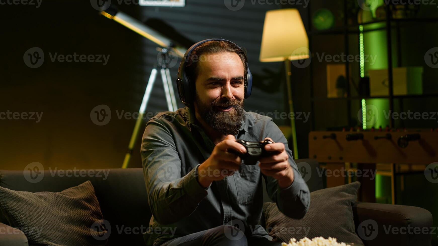 Cheerful gamer showing positive emotions after defeating all enemies while playing on gaming console. Man congratulating himself after winning videogame, feeling relieved, camera A photo
