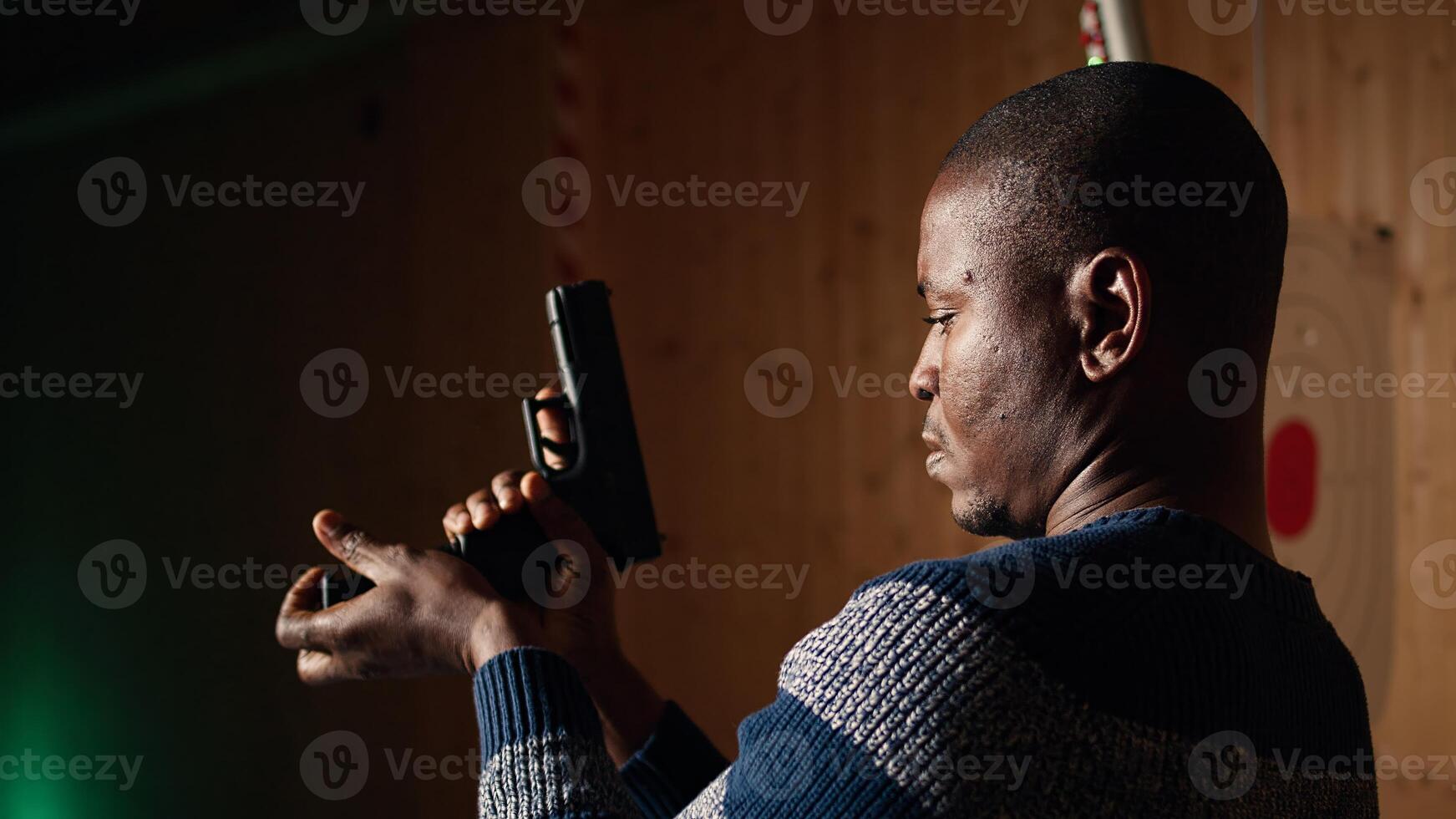Shooting range customer reloading pistol, preparing to shoot targets during recreational sport activity. Man at firing range loading pistol with ammunition, camera A close up photo