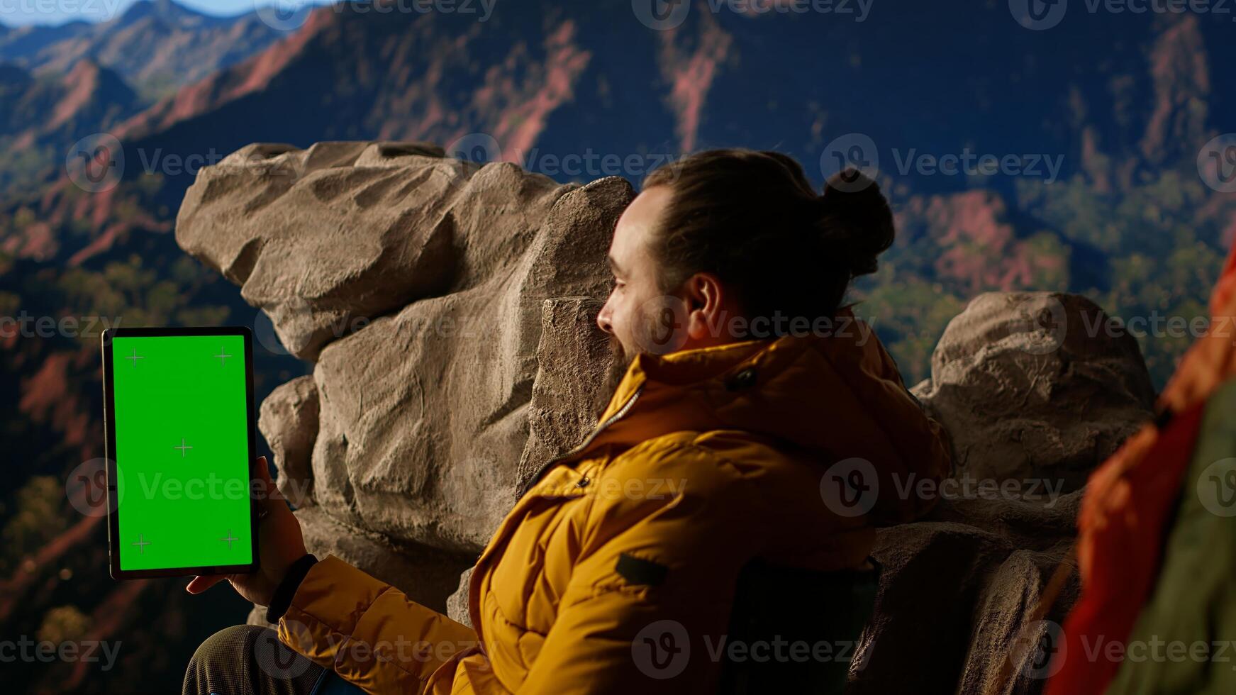 Adventure seeker stands at mountain peak next to isolated chroma key, looking at scenic view that stretches endlessly before him. Fresh air and breathtaking landscape. Camera A. photo