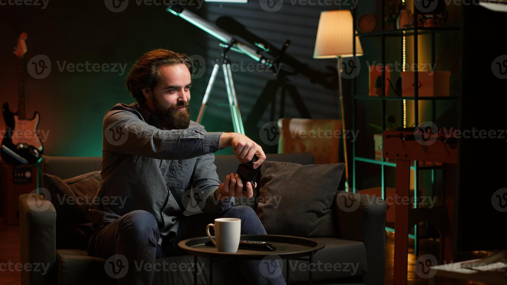 Energetic gamer arrives home, gaming during leisure time. Enthusiastic man entering room, jumping on couch, excited to play videogame on console, relaxing after hard day at work, camera A photo