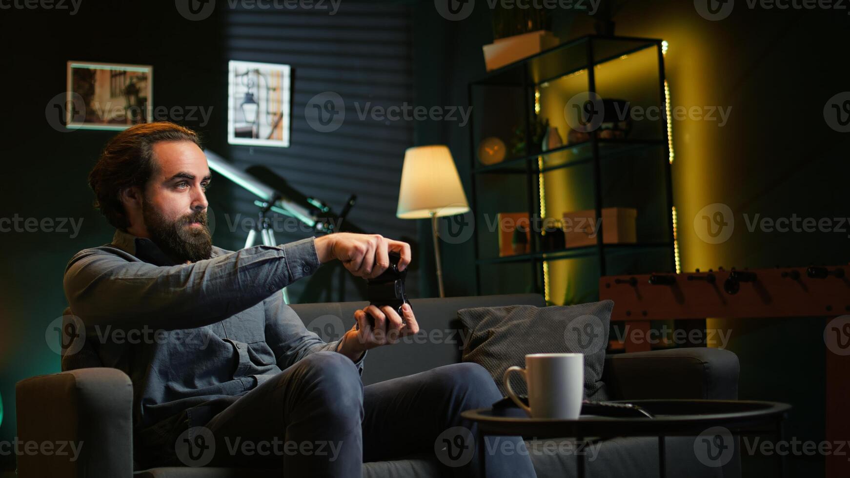 Man enjoying playing videogame in neon lit room, holding controller. Gamer participating in online esports competition using professional gamepad for better victory chances, camera B photo