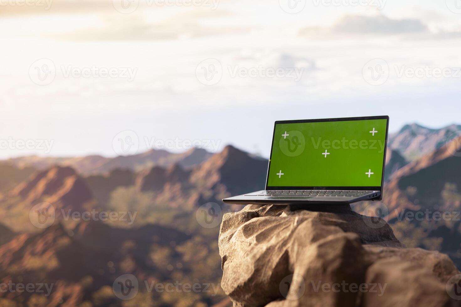 Dramatic mountain range stretches across horizon with green screen laptop, offering spectacular scenic view for hikers and adventurers. The rugged terrain is a challenge worth conquering. photo
