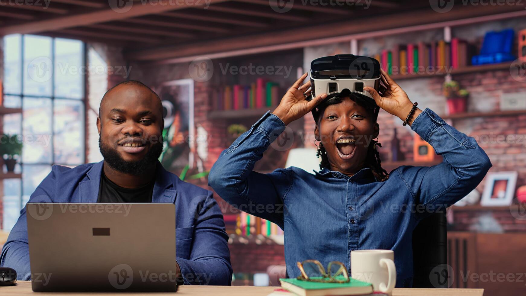 African American woman interacts with VR while boyfriend completes 3D animation on laptop. Freelancers couple integrating artificial intelligence and creativity. Camera B. photo