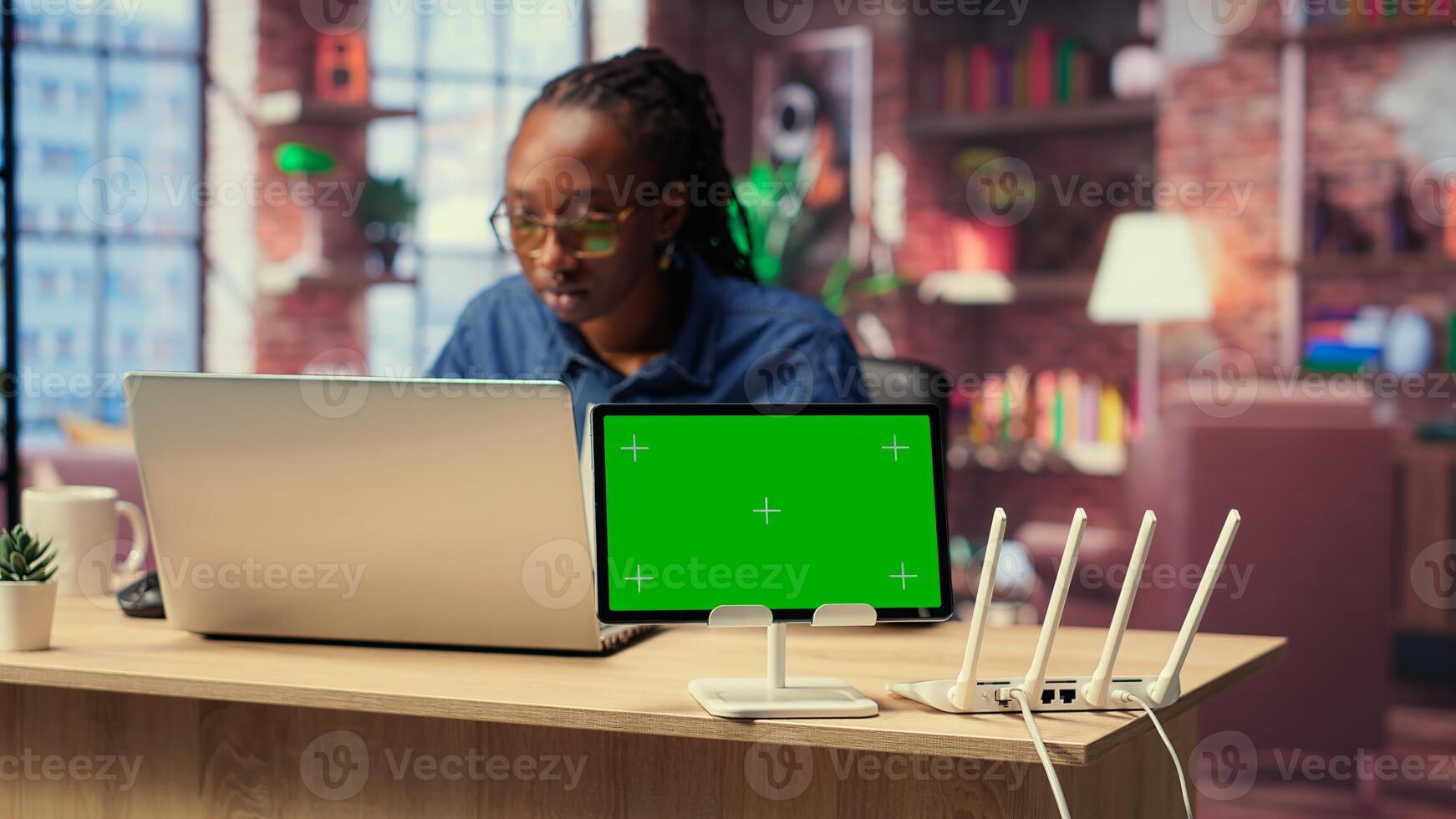 Female freelancer browses troubleshooting guide next to copy space, working on debugging router issues to restore home network. Young woman struggles to solve tasks. Camera B. photo