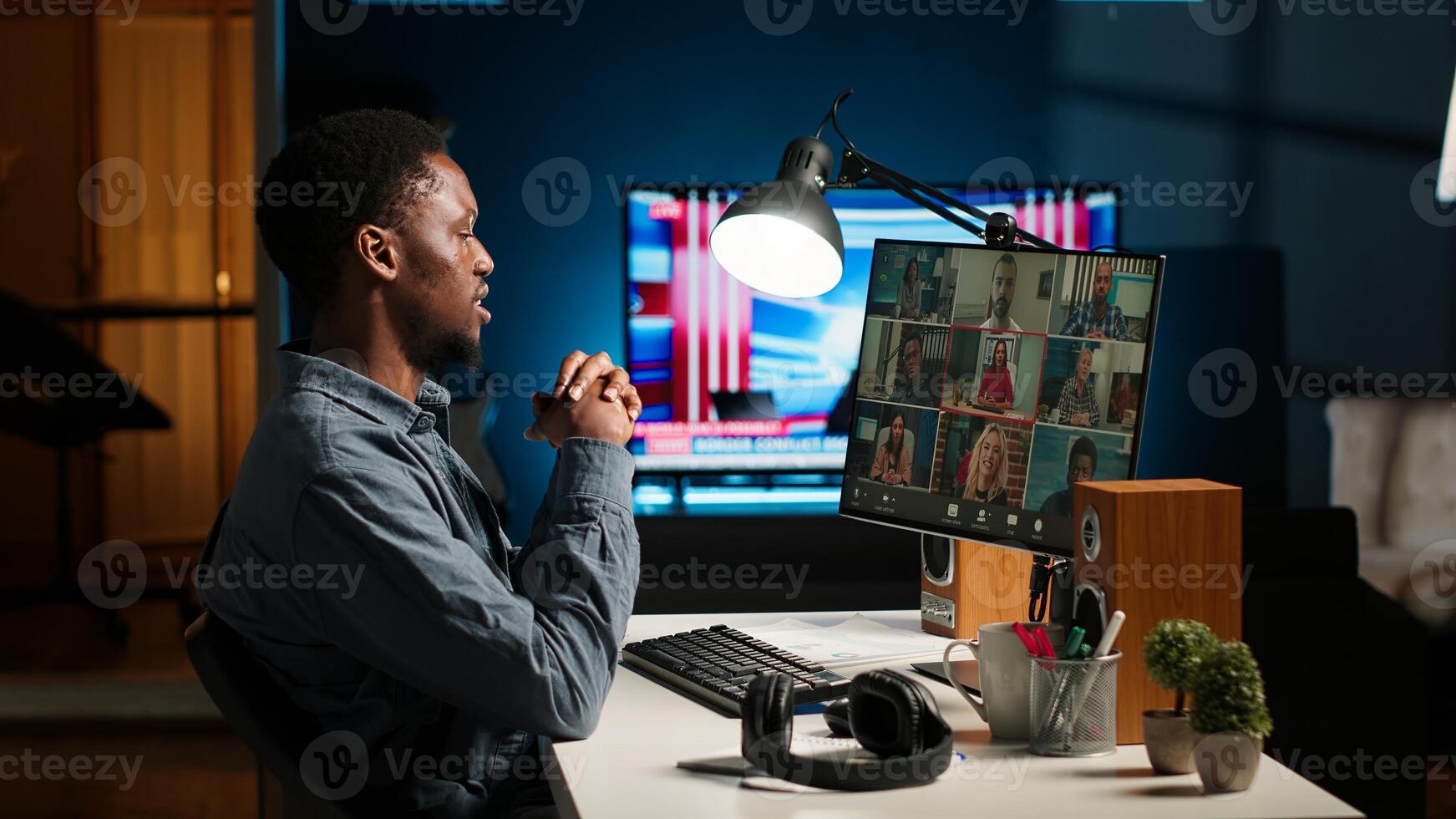 Black man meeting with group of individuals on web conference, using technology for virtual communication. Freelancer working remotely, online meetings or classes in cozy home. Camera B. photo