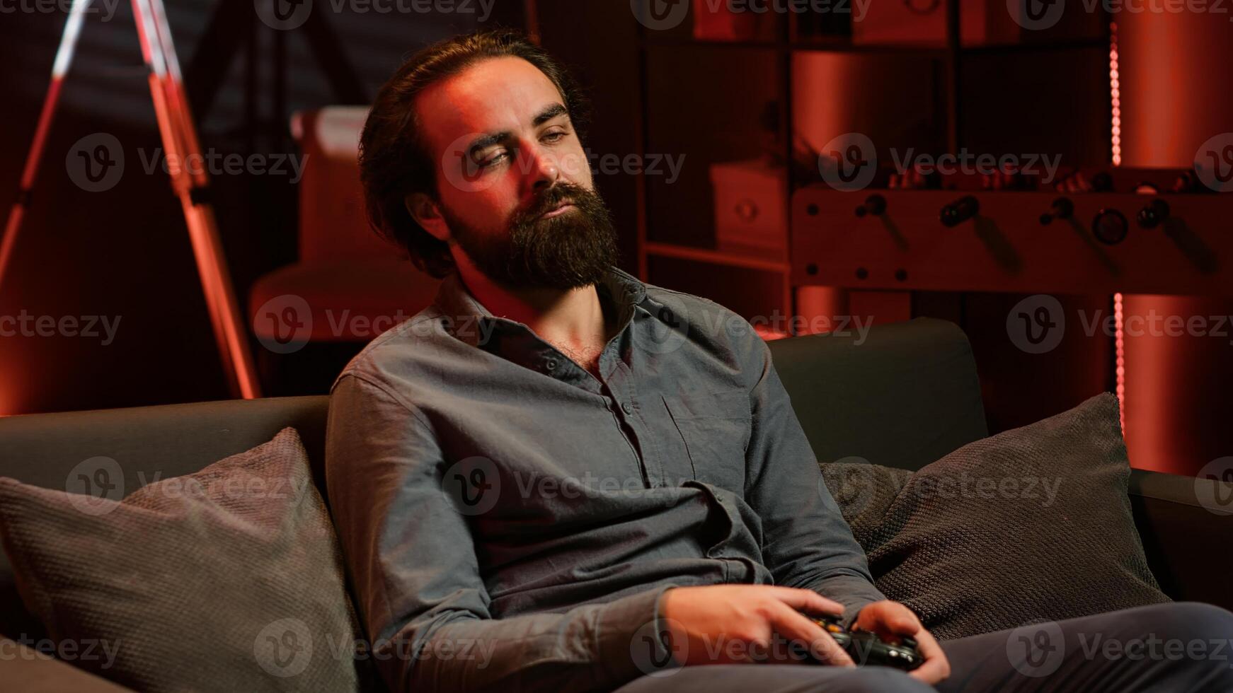 Bored gamer using controller, eating popcorn, living sedentary lifestyle. Lazy man in home theatre playing videogames and consuming snacks, sitting on couch, camera A photo