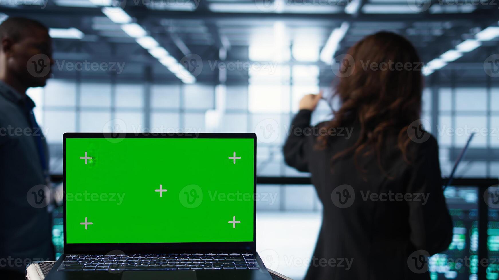 Mockup laptop in front of software developers walking in data center, reviewing equipment diagnostics. Close up of isolated screen notebook next to IT professionals in server farm photo