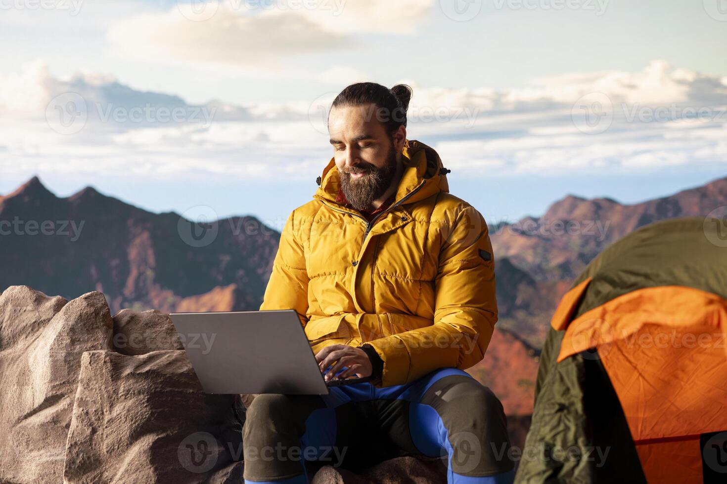 Young explorer keeps working at top of mountain with internet everywhere, enjoying global connectivity and productivity on hill summit. High speed strong signal during hike. photo