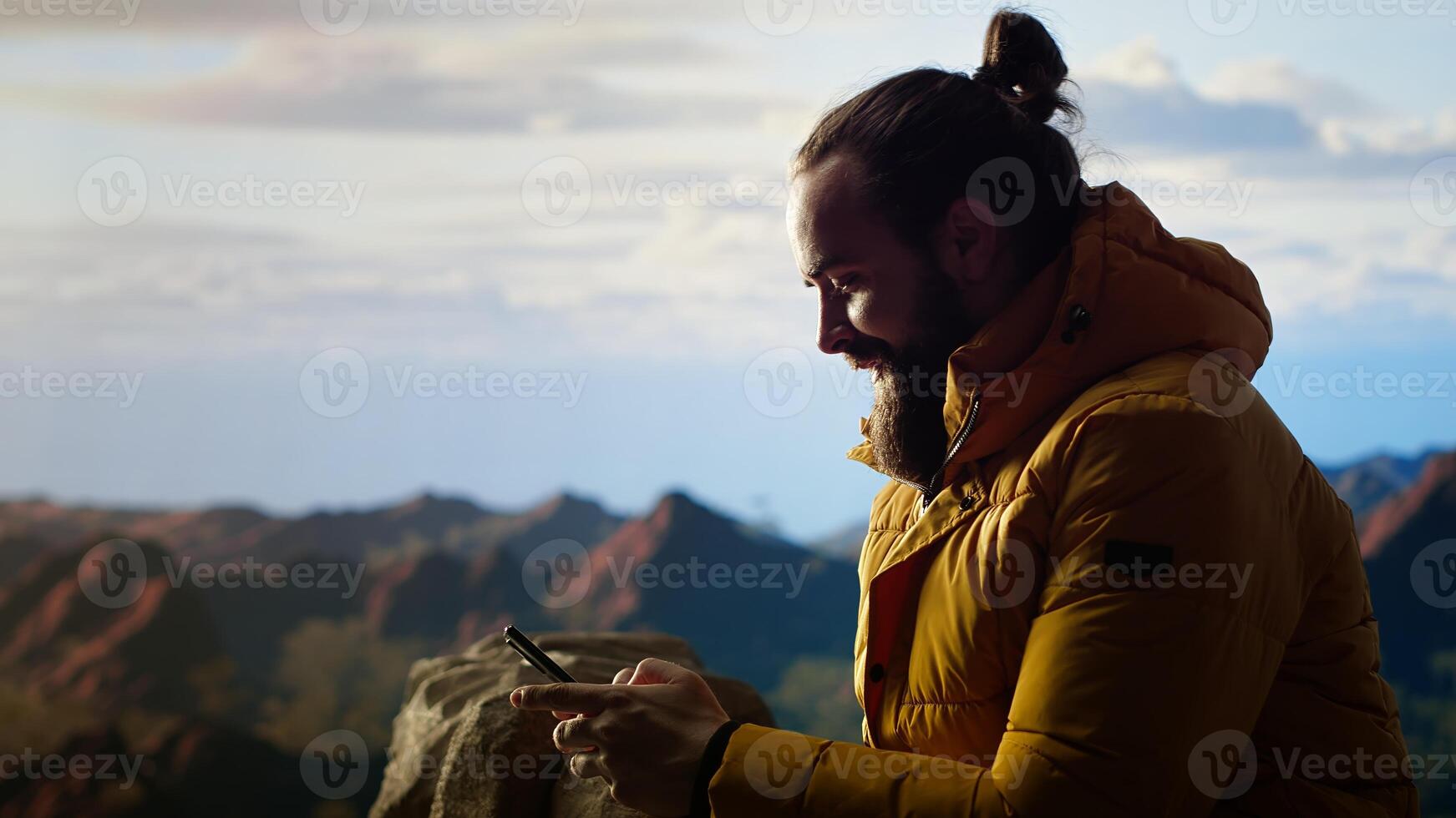 Trekker enjoys quiet moment in mountains scrolling phone app, where high altitude air and breathtaking view encourage mindfulness. Relaxation and self improvement. Camera B. photo