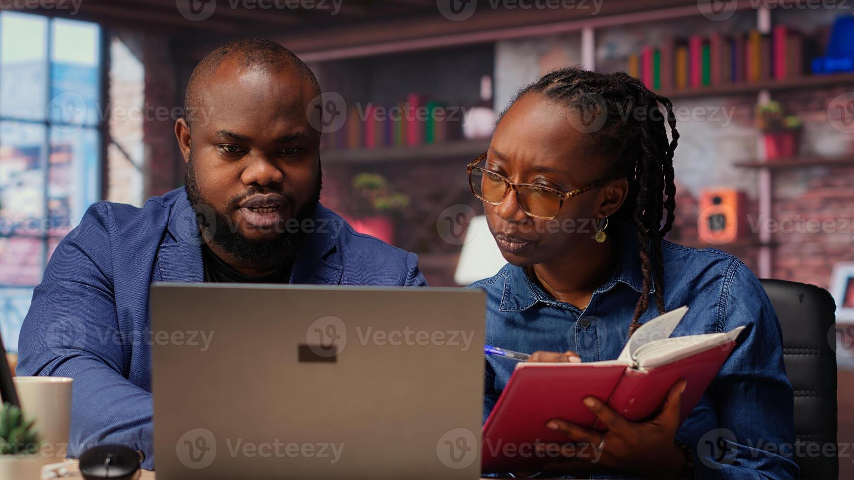 Remote employees organizing calendar appointments using laptop and ledger, checking papers and synchronizing important tasks on schedule. Man and woman review files at home. Camera B. photo