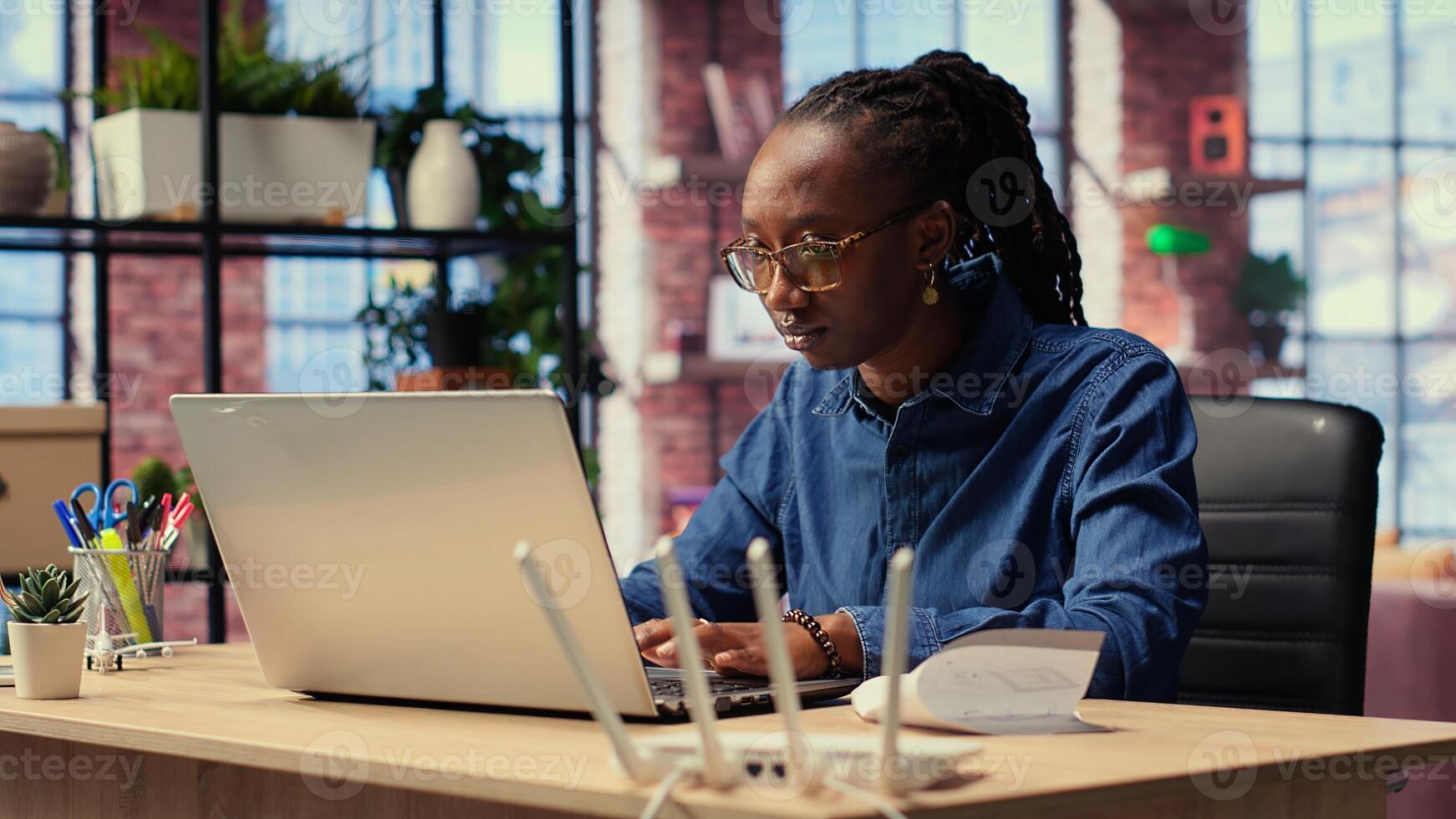 Irritated African American girl struggles in reaching internet provider to help fix signal loss, freelancer working at home with unstable Wi Fi connection. Camera B. photo
