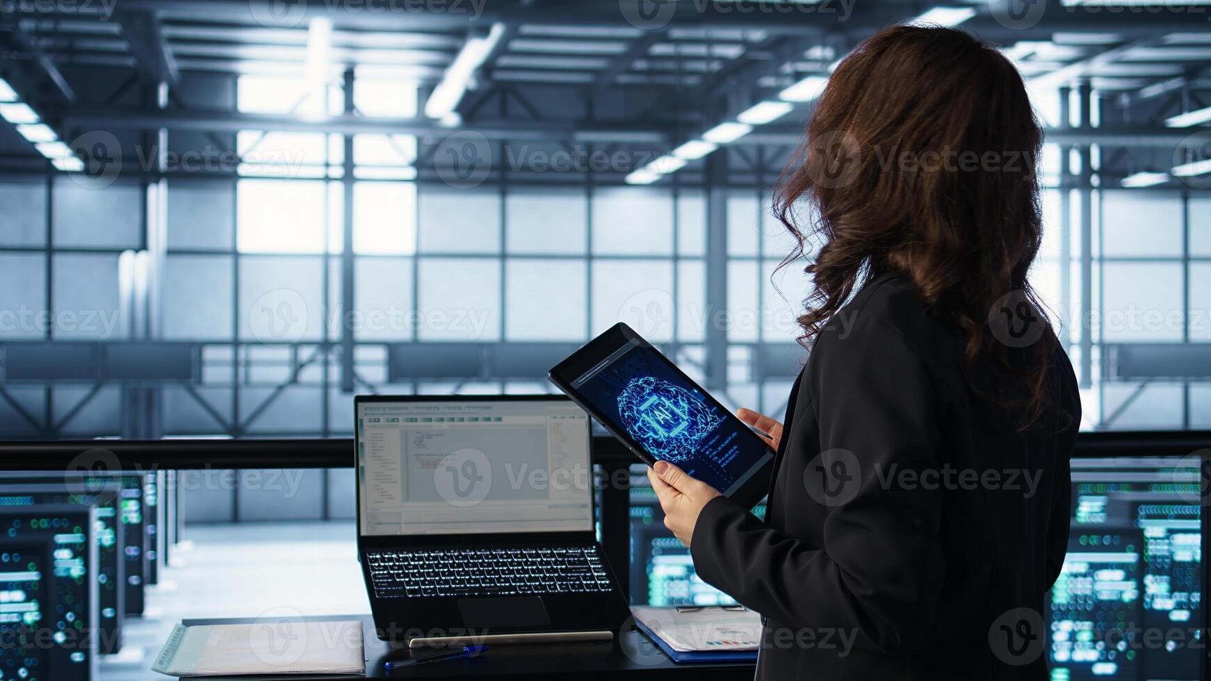 Technician with tablet integrating AI driven automation tools, running predictive maintenance routines. Woman ensuring continuous uptime of server room, managing data flows, camera B photo