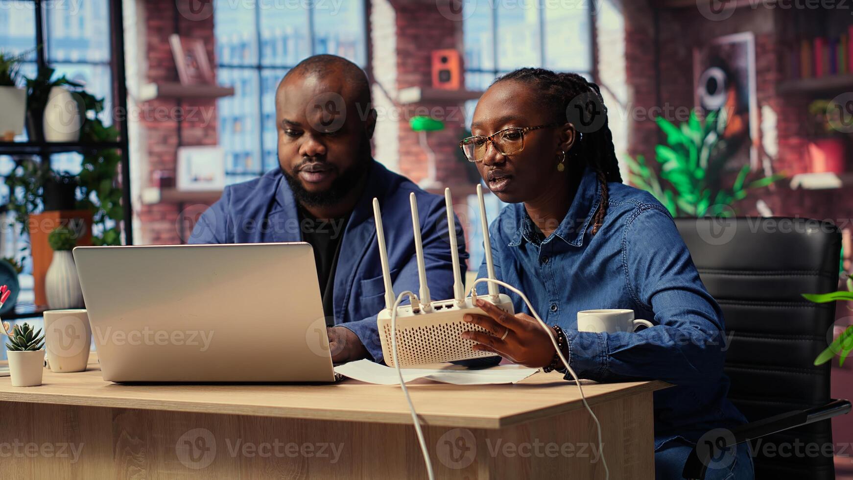 African American couple at home office troubleshooting WiFi modem and discussing solutions to fix weak connection affecting remote work productivity. Router guide files. Camera B. photo