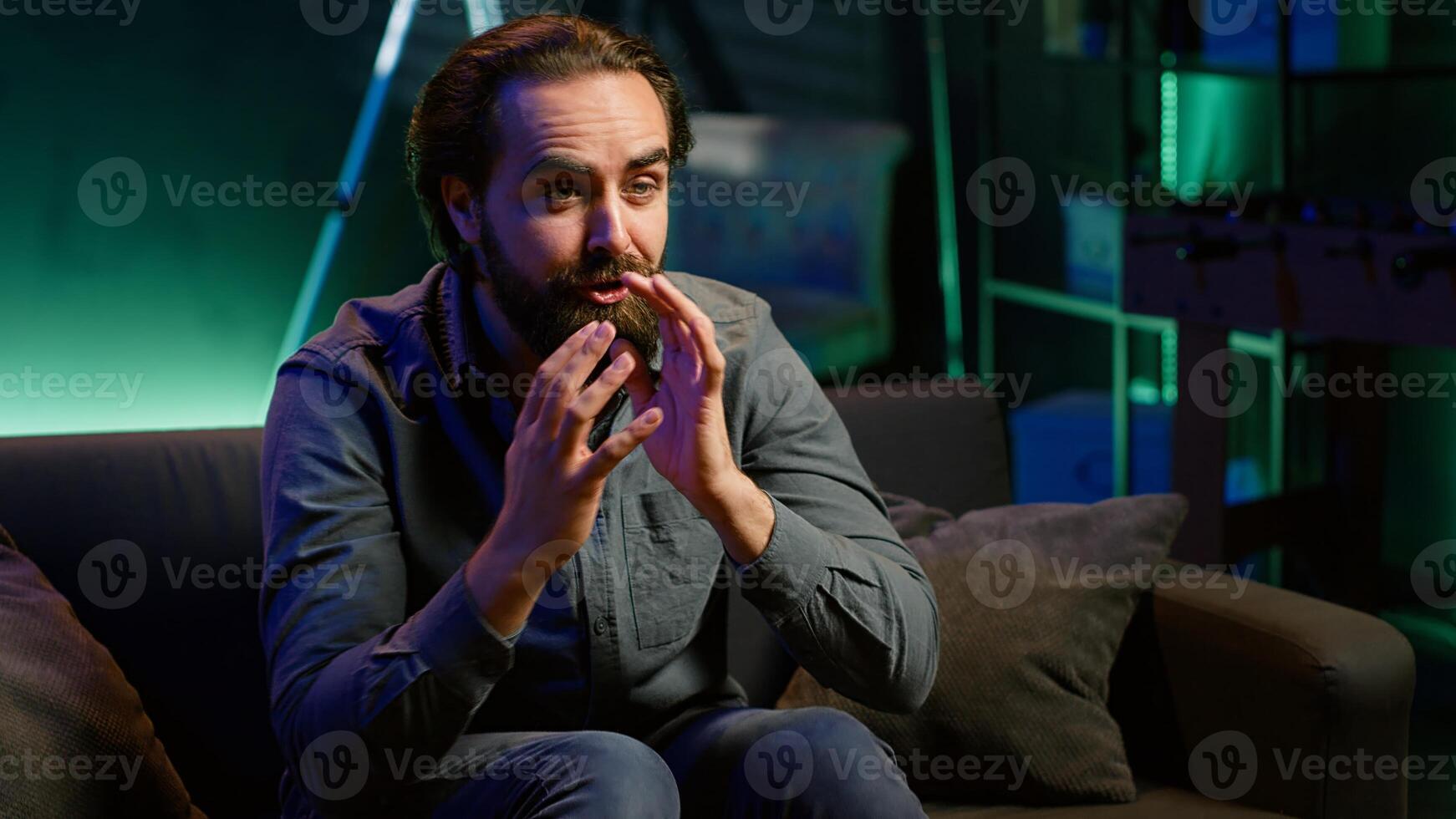 Supporter watching live sports game, raging on couch in anger seeing team mistake. Angry man looking at football match, fuming and releasing pent up emotions, camera A photo