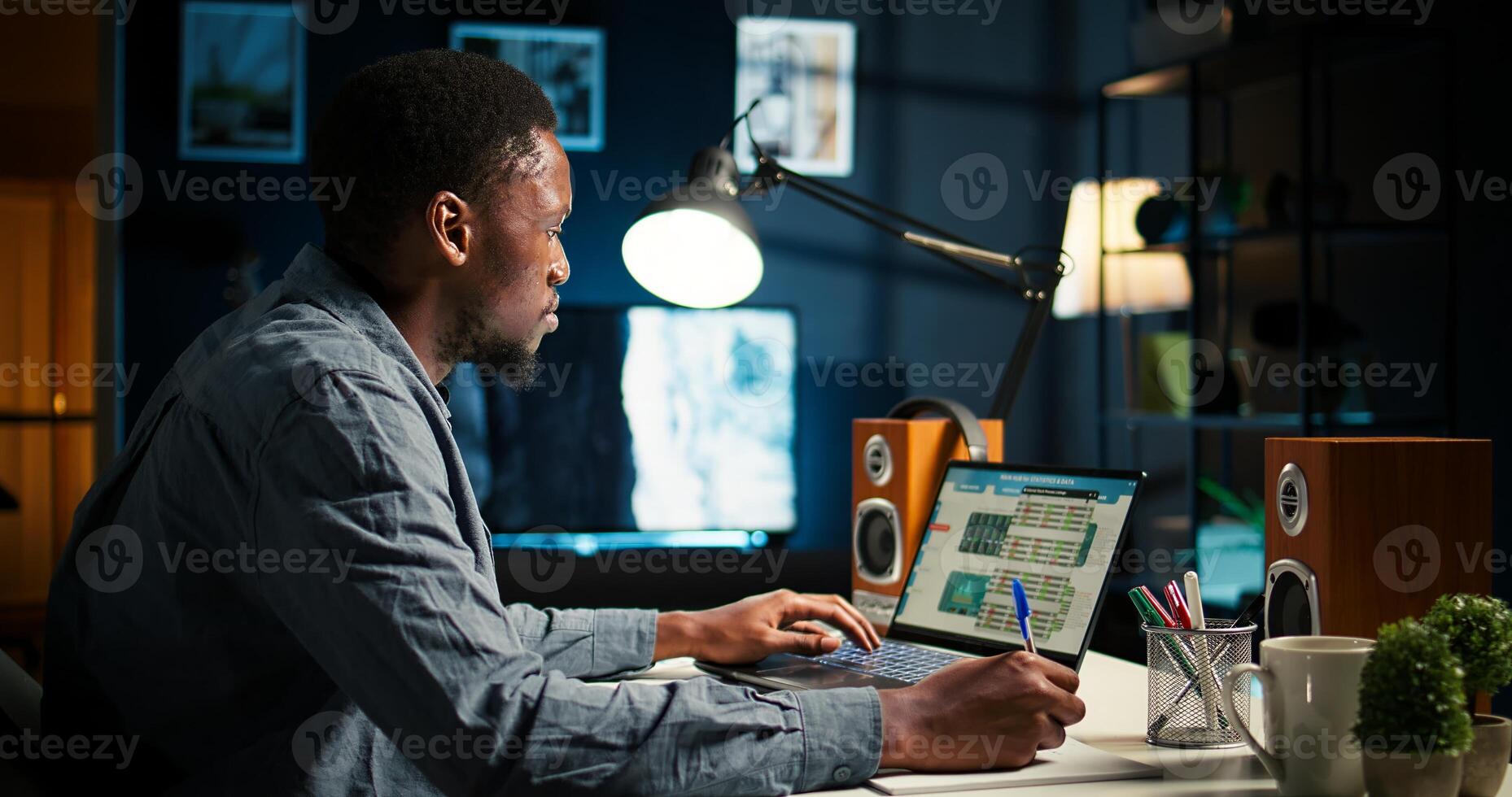 Self employed man multitasking at home taking handwritten notes and browsing web for project research. Managing schedule and tasks with planner to boost productivity. Camera A. photo