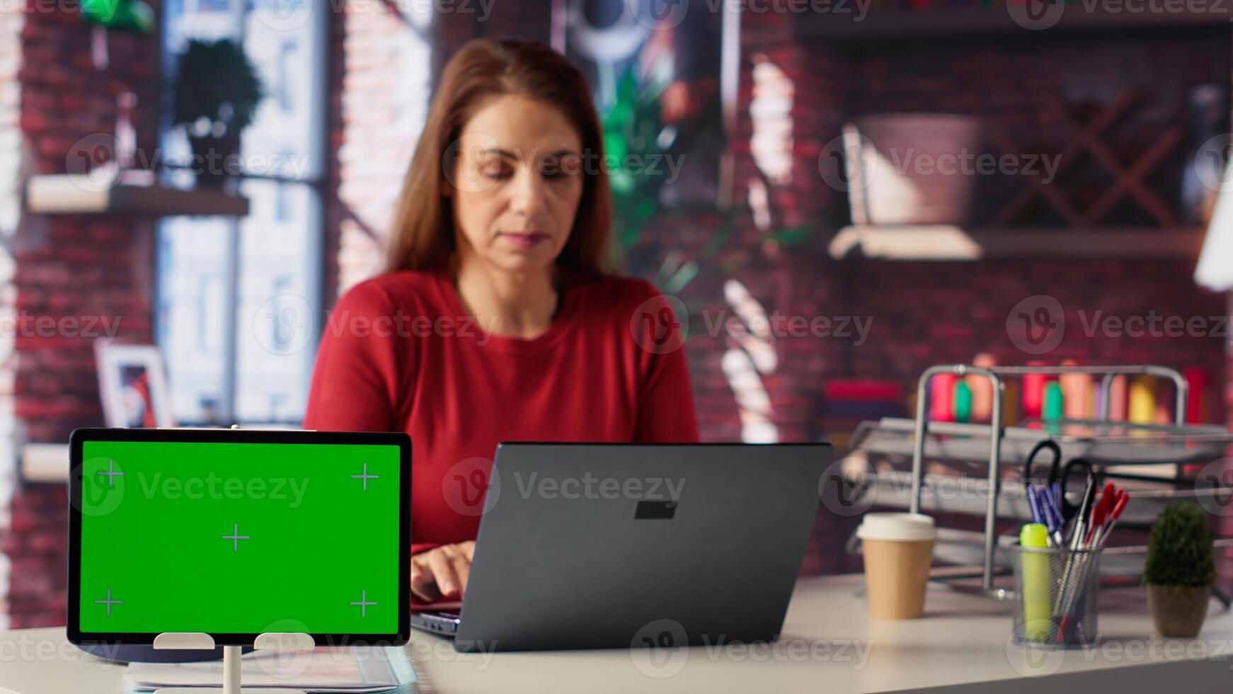 Woman reading forms and papers next to isolated screen and studying handwritten notes, surfing web and staying connected for freelance work tasks. Multitasking online. Camera A. photo