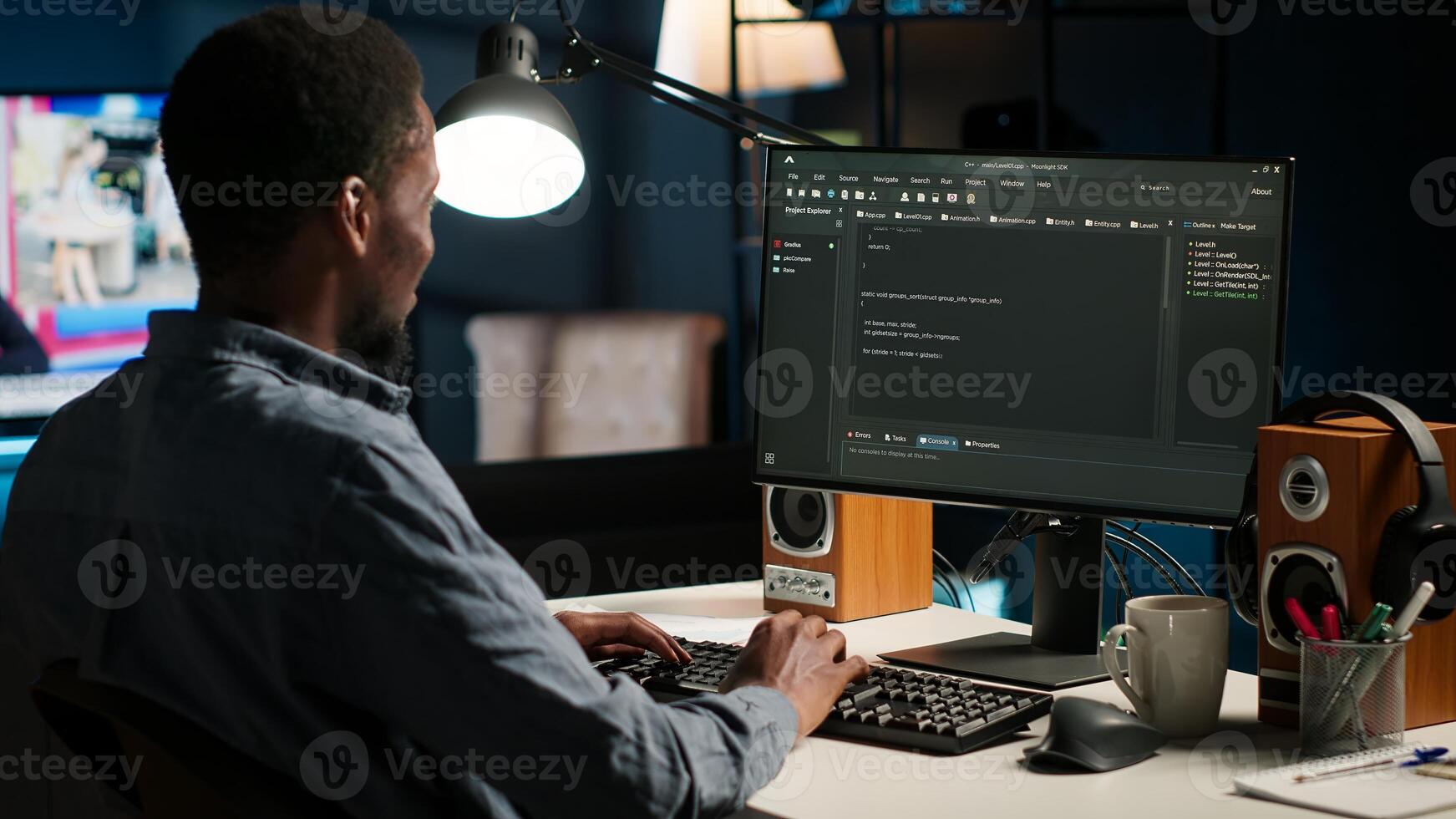 Black man programmer manages code and scripts in artificial intelligence and machine learning on dual monitors computer setup. Freelancer uses pc to guarantee cyber security. Camera B. photo