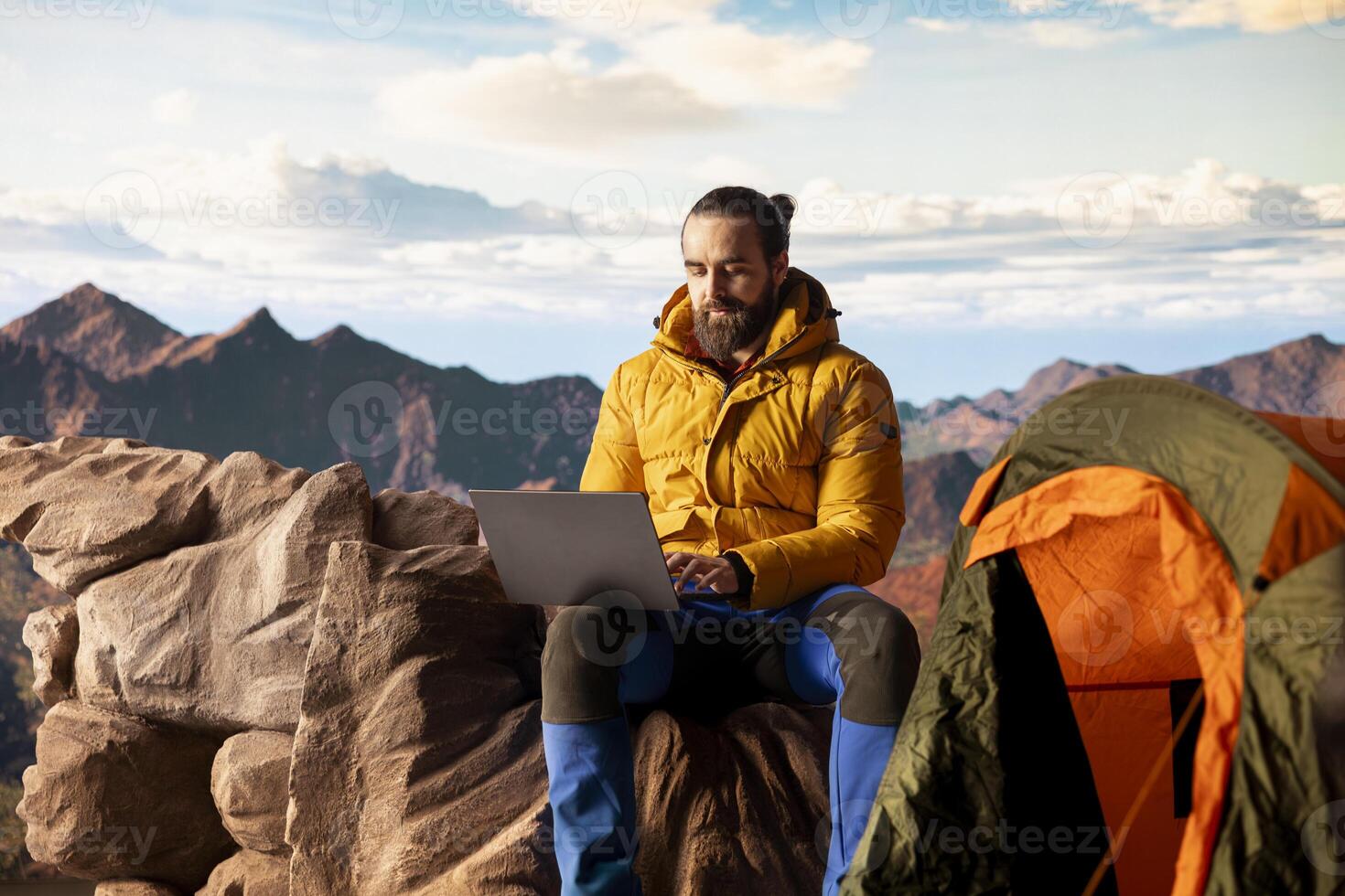 Online entrepreneur with technology reliance on mountain top, always connected workaholic hiker admires scenic landscape. Remote access with high connectivity and speed. photo
