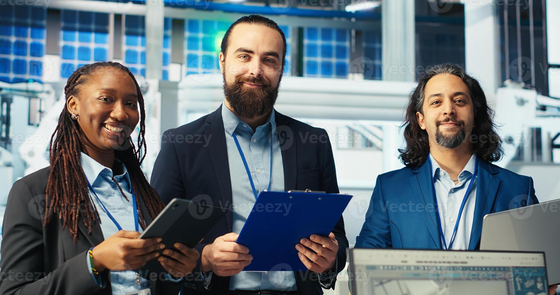 Portrait of cheerful experts in factory reviewing performance of robot arms placing solar panels on assembly lines. Team of business partners inspecting photovoltaics machinery photo