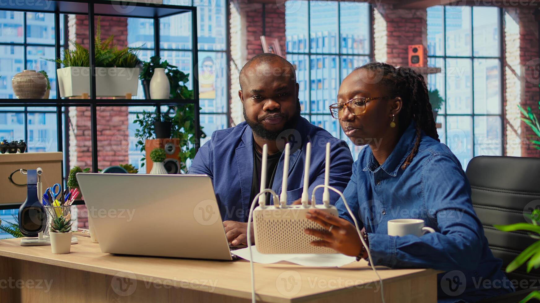 African American couple at home office troubleshooting WiFi modem and discussing solutions to fix weak connection affecting remote work productivity. Router guide files. Camera A. photo